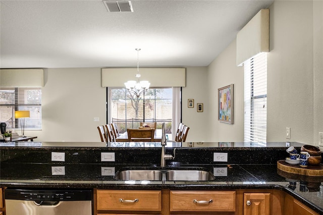 kitchen featuring sink, dishwasher, decorative light fixtures, dark stone counters, and a chandelier