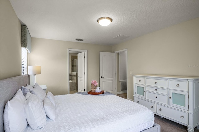 bedroom with a textured ceiling and ensuite bath