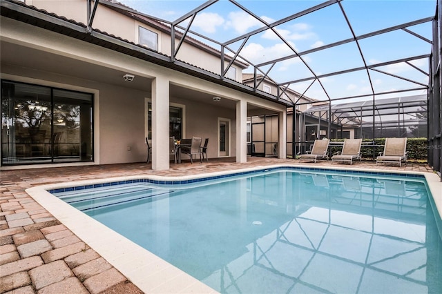 view of swimming pool featuring glass enclosure and a patio area