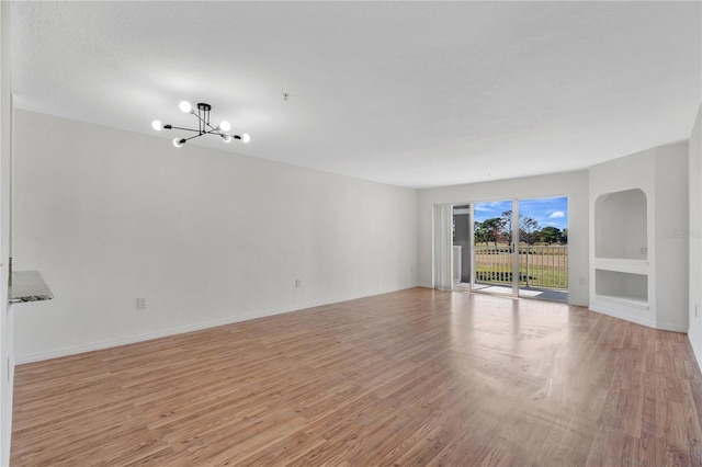 spare room with an inviting chandelier and light hardwood / wood-style floors