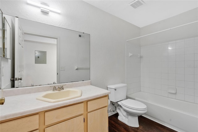 full bathroom with wood-type flooring, tiled shower / bath combo, vanity, electric panel, and toilet