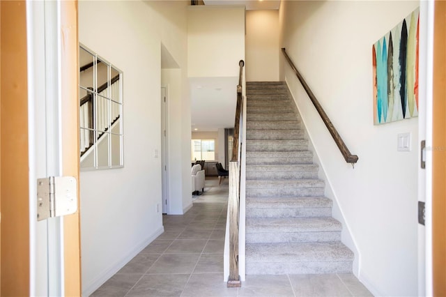 staircase featuring a high ceiling and tile patterned floors