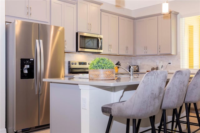 kitchen with appliances with stainless steel finishes, a breakfast bar, tasteful backsplash, hanging light fixtures, and a center island