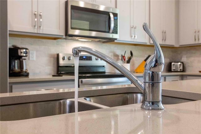 interior details with tasteful backsplash, light stone counters, and white cabinets