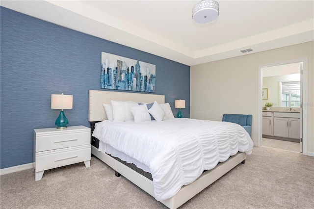 bedroom featuring connected bathroom, light colored carpet, and sink