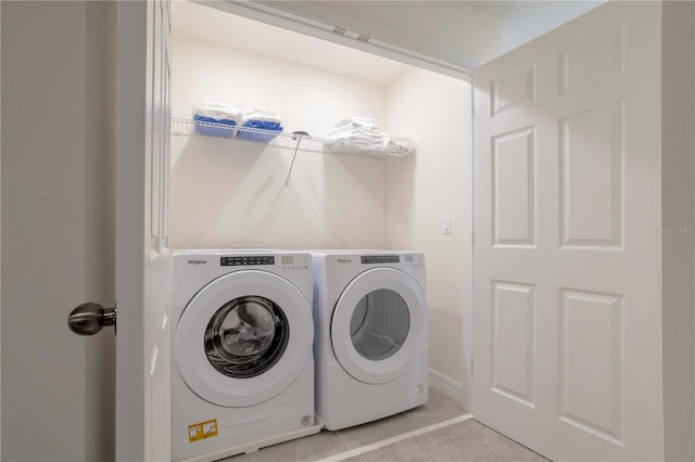 clothes washing area featuring light tile patterned floors and washing machine and clothes dryer