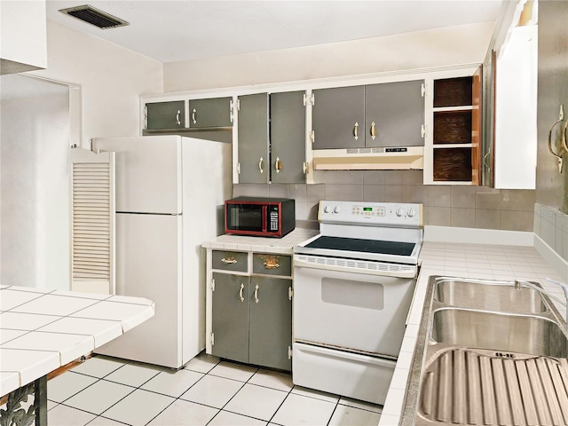 kitchen with sink, tasteful backsplash, tile countertops, gray cabinets, and white appliances