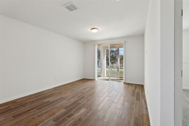 spare room with dark hardwood / wood-style flooring and a textured ceiling