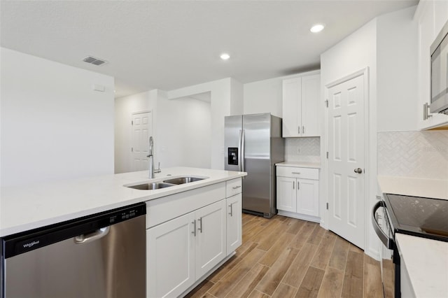 kitchen featuring sink, decorative backsplash, white cabinets, and appliances with stainless steel finishes