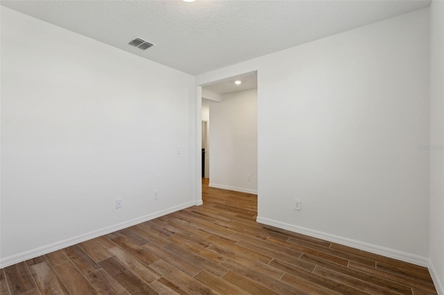 spare room featuring dark wood-type flooring and a textured ceiling