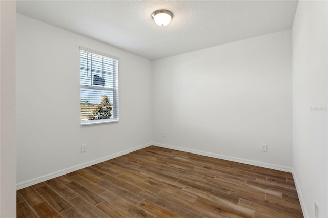 unfurnished room with dark wood-type flooring and a textured ceiling