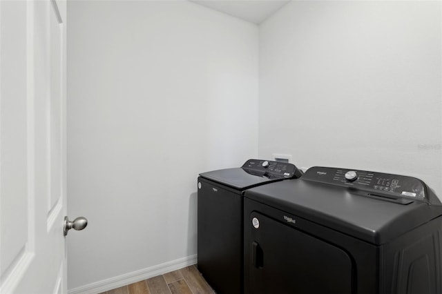 laundry room with washing machine and clothes dryer and light hardwood / wood-style flooring