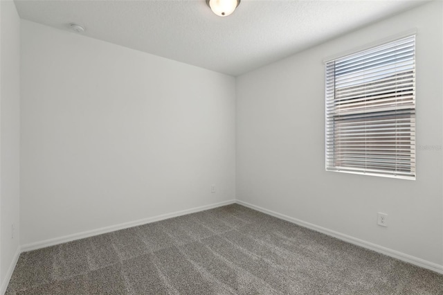 spare room with a textured ceiling and dark colored carpet