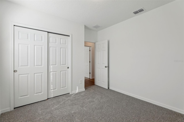 unfurnished bedroom featuring carpet, a textured ceiling, and a closet