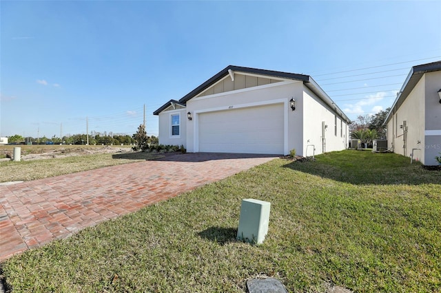 view of front of home with a garage, cooling unit, and a front lawn