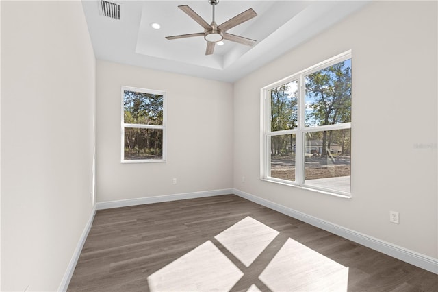 unfurnished room with ceiling fan, dark hardwood / wood-style floors, and a raised ceiling