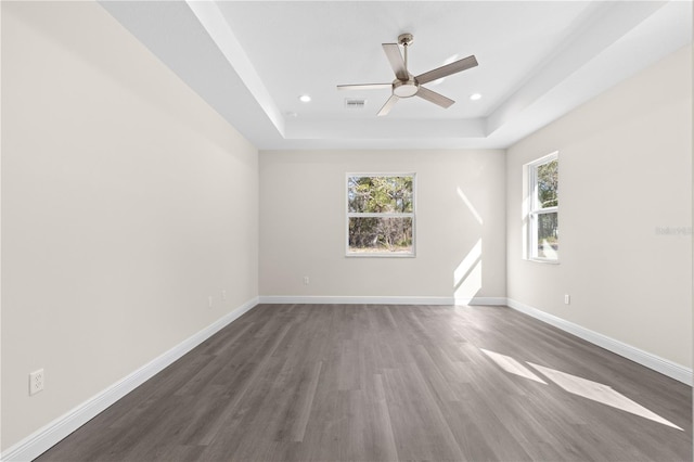 spare room featuring ceiling fan, dark hardwood / wood-style flooring, and a raised ceiling