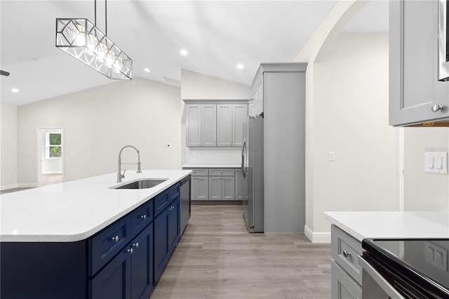 kitchen with sink, appliances with stainless steel finishes, a center island with sink, decorative light fixtures, and vaulted ceiling