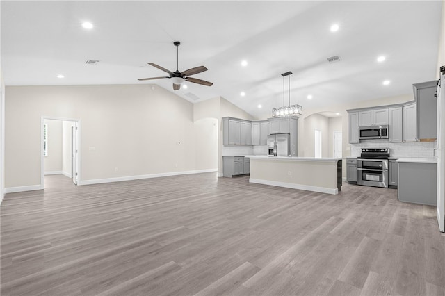 kitchen with gray cabinets, ceiling fan, appliances with stainless steel finishes, a kitchen island, and decorative light fixtures