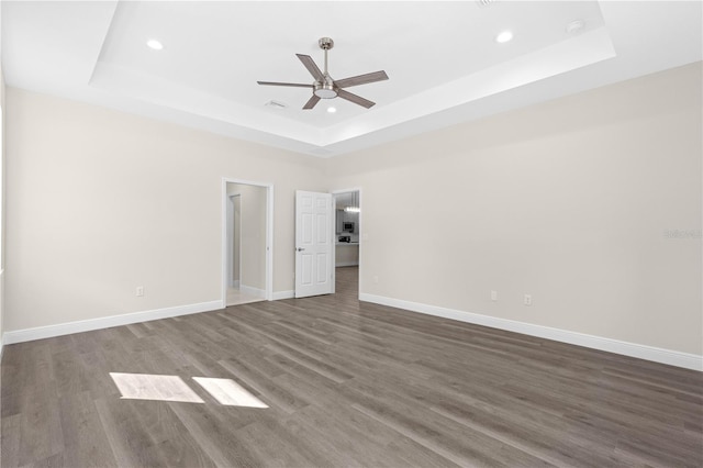 unfurnished bedroom featuring dark hardwood / wood-style flooring, a raised ceiling, and ceiling fan