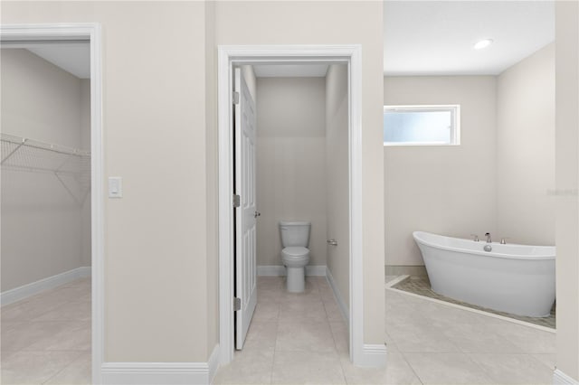 bathroom with toilet, tile patterned flooring, and a washtub