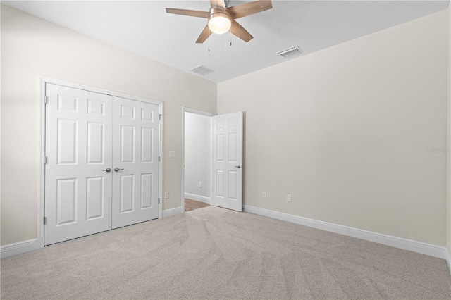 unfurnished bedroom featuring light carpet, ceiling fan, and a closet