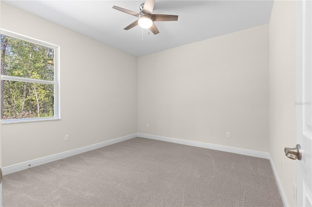 carpeted spare room featuring ceiling fan