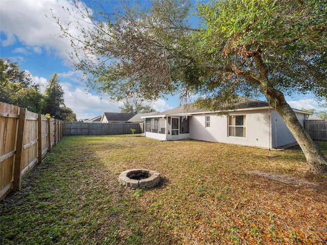 back of house featuring an outdoor fire pit, a yard, and a sunroom