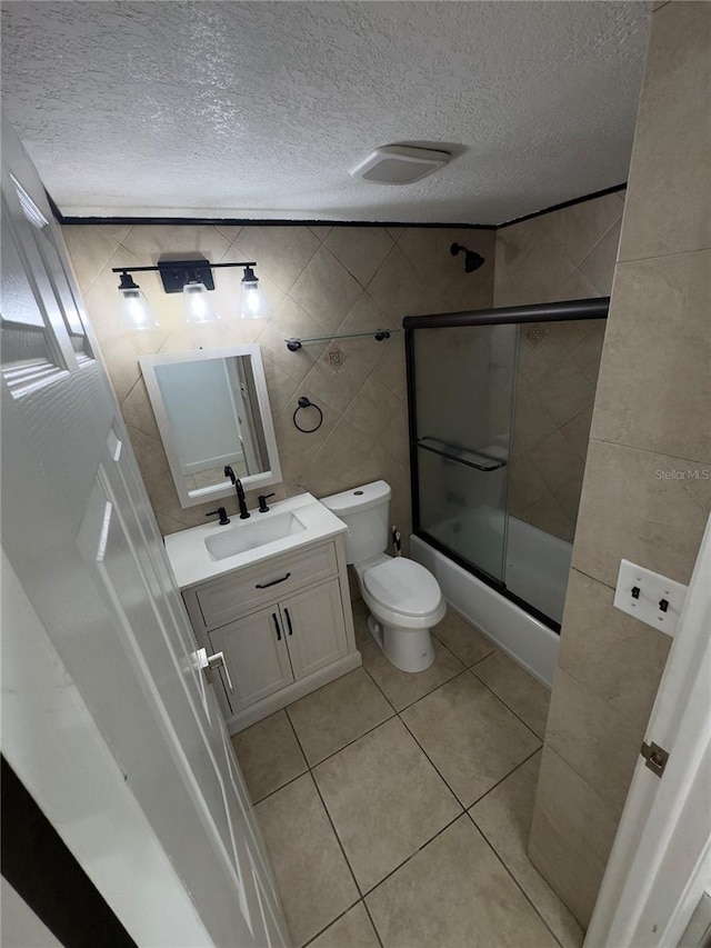 full bathroom with toilet, a textured ceiling, vanity, enclosed tub / shower combo, and tile patterned flooring