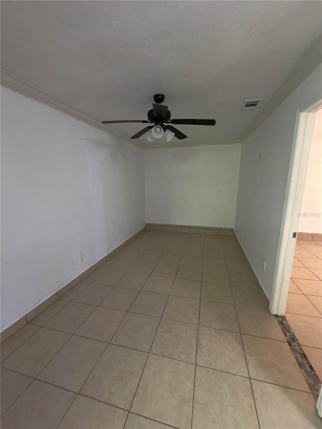 empty room featuring light tile patterned flooring, ceiling fan, ornamental molding, and a textured ceiling