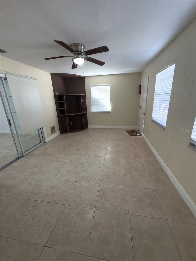 tiled spare room featuring a textured ceiling, plenty of natural light, and ceiling fan