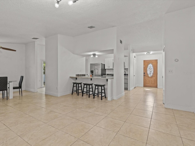 interior space featuring light tile patterned flooring, ceiling fan, and a textured ceiling