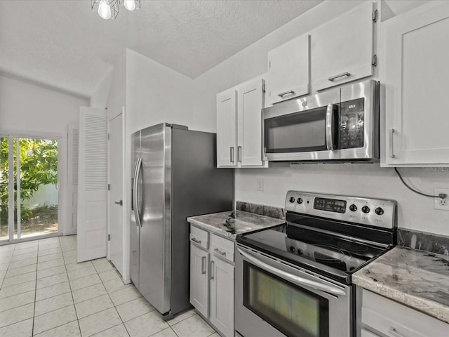 kitchen featuring appliances with stainless steel finishes, light tile patterned floors, a textured ceiling, and white cabinets