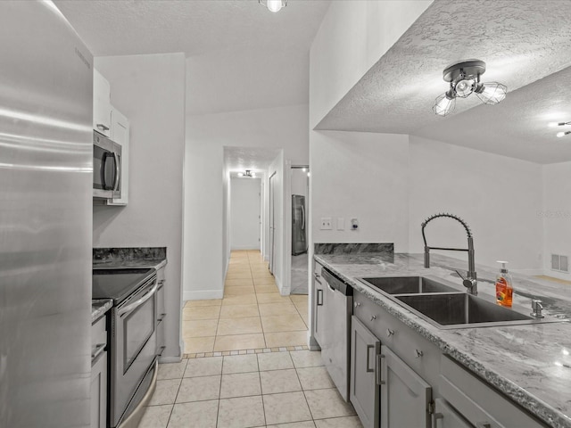 kitchen with light tile patterned flooring, sink, a textured ceiling, appliances with stainless steel finishes, and gray cabinets