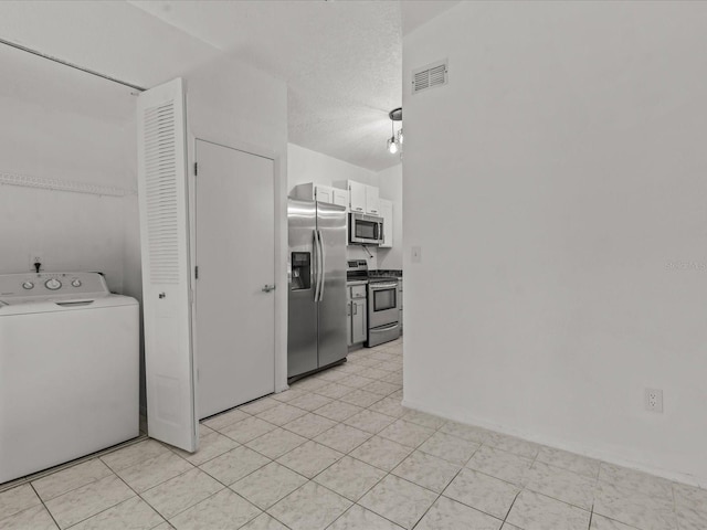 kitchen with washer / dryer, white cabinets, a textured ceiling, and appliances with stainless steel finishes