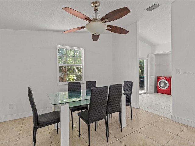 dining room featuring washer / clothes dryer, light tile patterned floors, vaulted ceiling, and a textured ceiling