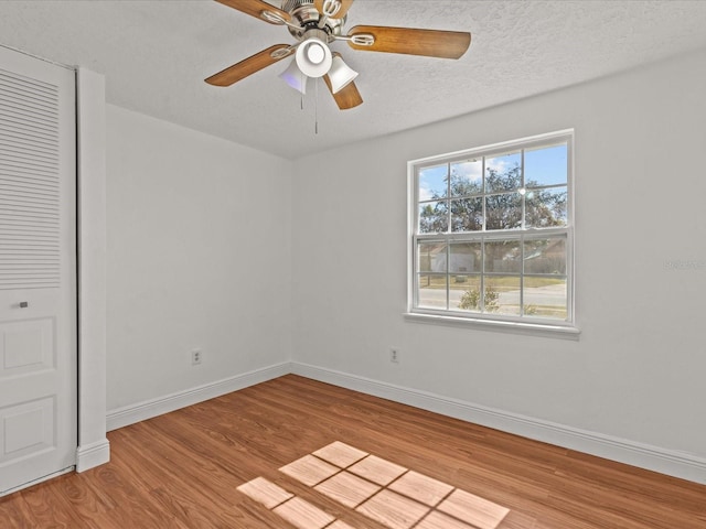 empty room with ceiling fan, a textured ceiling, and light wood-type flooring