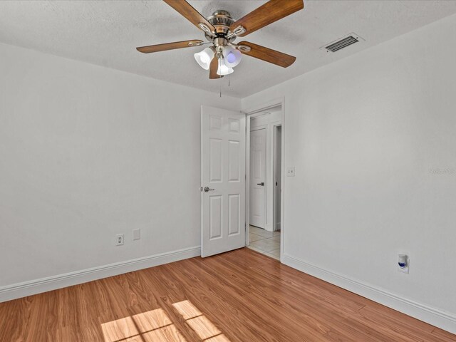 unfurnished room with ceiling fan, a textured ceiling, and light wood-type flooring