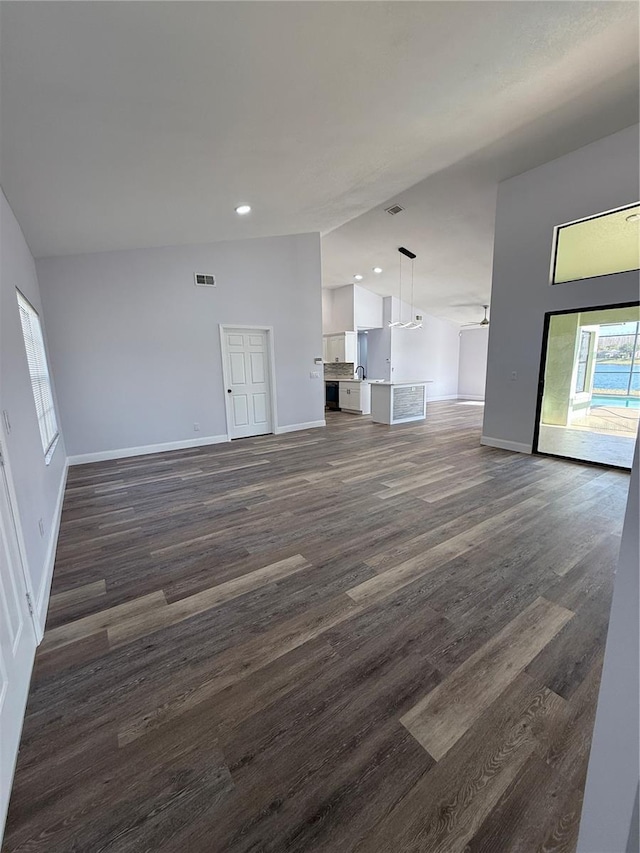 unfurnished living room with dark hardwood / wood-style flooring and vaulted ceiling