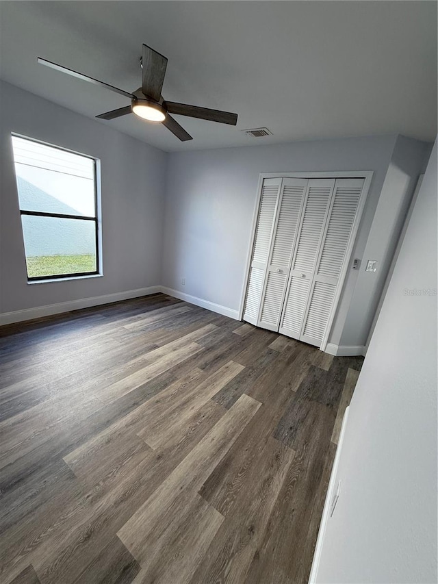 unfurnished bedroom featuring dark hardwood / wood-style floors, ceiling fan, and a closet