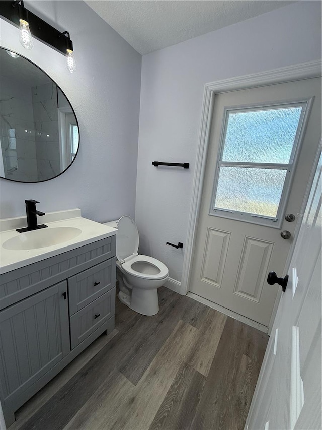 bathroom with wood-type flooring, vanity, a textured ceiling, and toilet