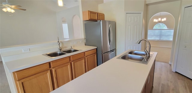 kitchen with light hardwood / wood-style flooring, sink, stainless steel fridge, and hanging light fixtures