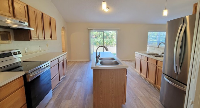 kitchen with stainless steel appliances, sink, a center island with sink, and decorative light fixtures