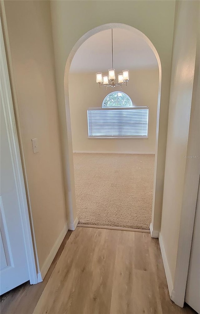 hall with wood-type flooring and a chandelier