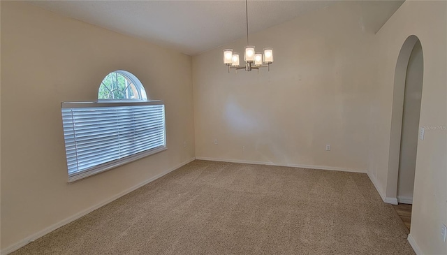 carpeted spare room featuring vaulted ceiling and a chandelier