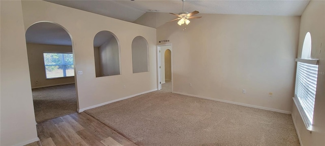 spare room with ceiling fan, vaulted ceiling, and light wood-type flooring