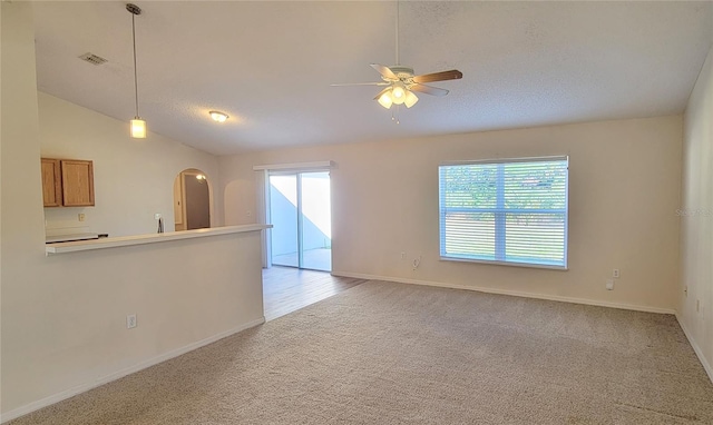 unfurnished living room with ceiling fan, vaulted ceiling, and light carpet