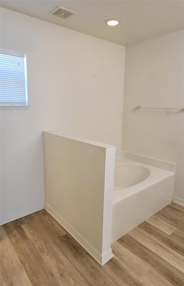 bathroom with hardwood / wood-style flooring and tiled tub