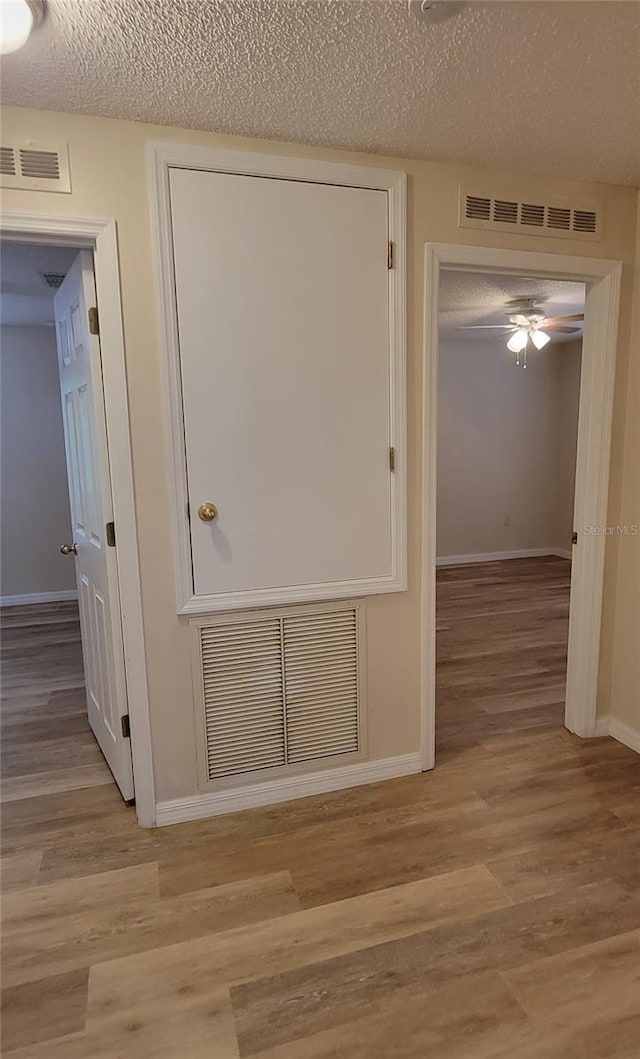 corridor featuring light hardwood / wood-style floors and a textured ceiling