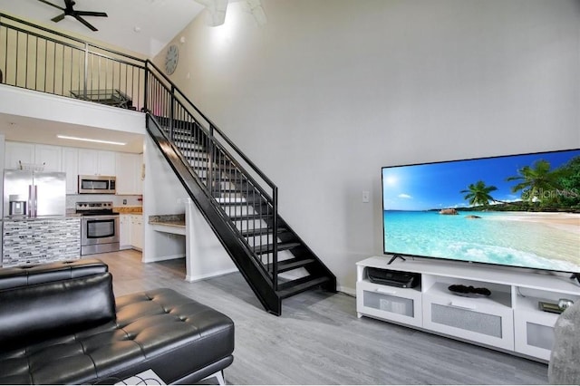 living room featuring a high ceiling, wood-type flooring, and ceiling fan